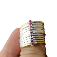 Load image into Gallery viewer, A bold and unique wide ring featuring two 9k solid yellow gold bands and eight 1mm solid sterling silver matte-textured rings. The design is accentuated by a vertical sterling silver bar adorned with sparkling ruby stones, creating a striking and elegant statement piece.
