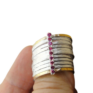 A bold and unique wide ring featuring two 9k solid yellow gold bands and eight 1mm solid sterling silver matte-textured rings. The design is accentuated by a vertical sterling silver bar adorned with sparkling ruby stones, creating a striking and elegant statement piece.
