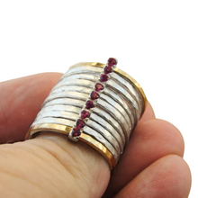 Load image into Gallery viewer, A bold and unique wide ring featuring two 9k solid yellow gold bands and eight 1mm solid sterling silver matte-textured rings. The design is accentuated by a vertical sterling silver bar adorned with sparkling ruby stones, creating a striking and elegant statement piece.
