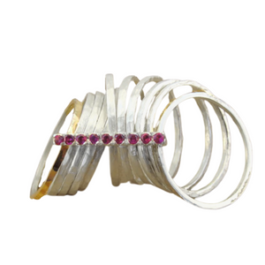 A bold and unique wide ring featuring two 9k solid yellow gold bands and eight 1mm solid sterling silver matte-textured rings. The design is accentuated by a vertical sterling silver bar adorned with sparkling ruby stones, creating a striking and elegant statement piece.
