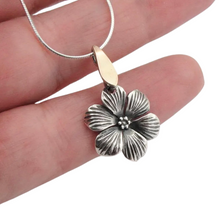 Load image into Gallery viewer, Elegant flower-shaped pendant crafted from sterling silver with a solid 9K yellow gold bail. The pendant features detailed, textured petals and a central floral design, adding a timeless and sophisticated touch. Shown hanging on a delicate silver chain.