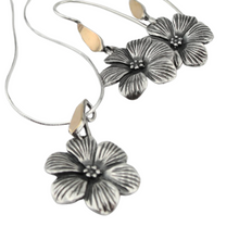 Load image into Gallery viewer, Elegant flower-shaped pendant crafted from sterling silver with a solid 9K yellow gold bail. The pendant features detailed, textured petals and a central floral design, adding a timeless and sophisticated touch. Shown hanging on a delicate silver chain.